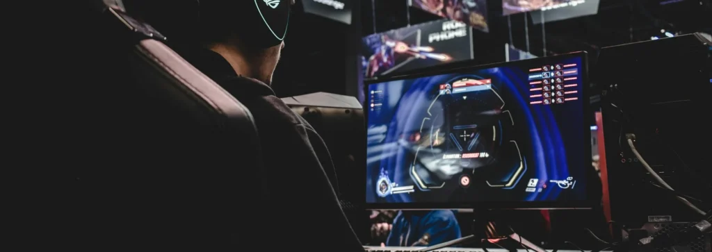Jogador de headset concentrado no monitor durante um campeonato, mão no mouse, no treino de mira dos pros