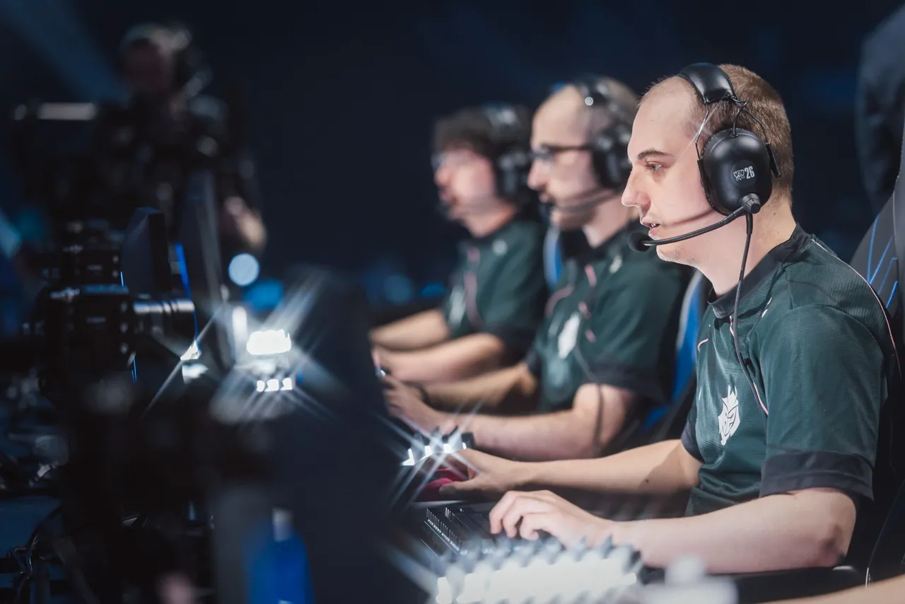 Jogadores da G2 Esports de headset, concentrados durante uma partida no palco do Worlds 2026