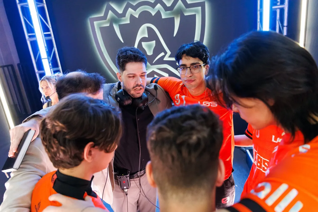 Jogadores da LØS, de camisa laranja, reunidos com a comissão técnica no palco do Worlds 2026 em Allen