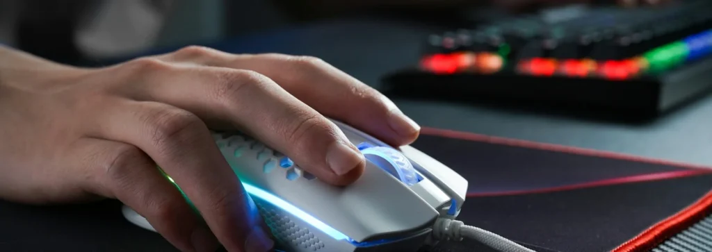 Mão no mouse gamer branco com luz RGB sobre o mousepad, ajuste de sensibilidade no Valorant